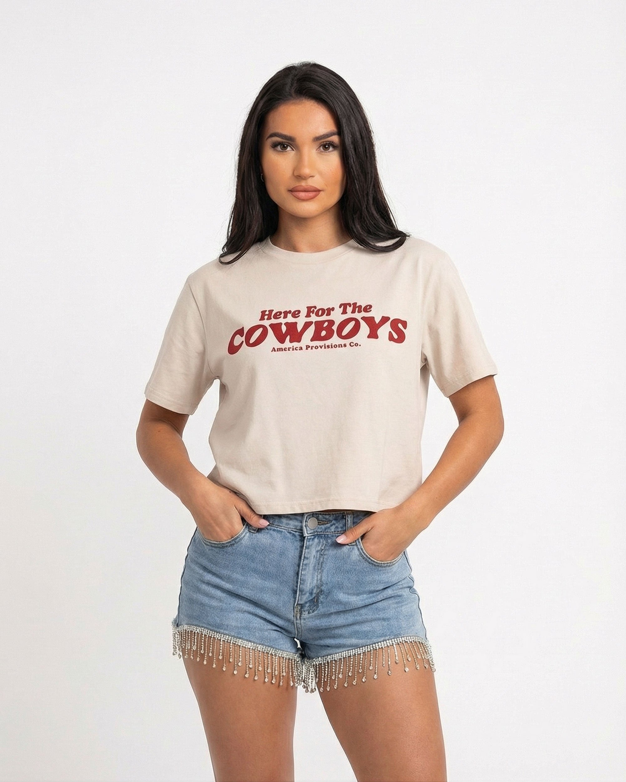 Model wearing Bone cropped t-shirt with bold red “Here For The Cowboys” Western graphic, structured boxy fit, heavy cotton fabric, America Provisions apparel product photo on a neutral background.