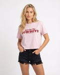 Model wearing Orchid colored cropped t-shirt with bold red “Here For The Cowboys” Western graphic, structured boxy fit, heavy cotton fabric, America Provisions apparel product photo on a neutral background.