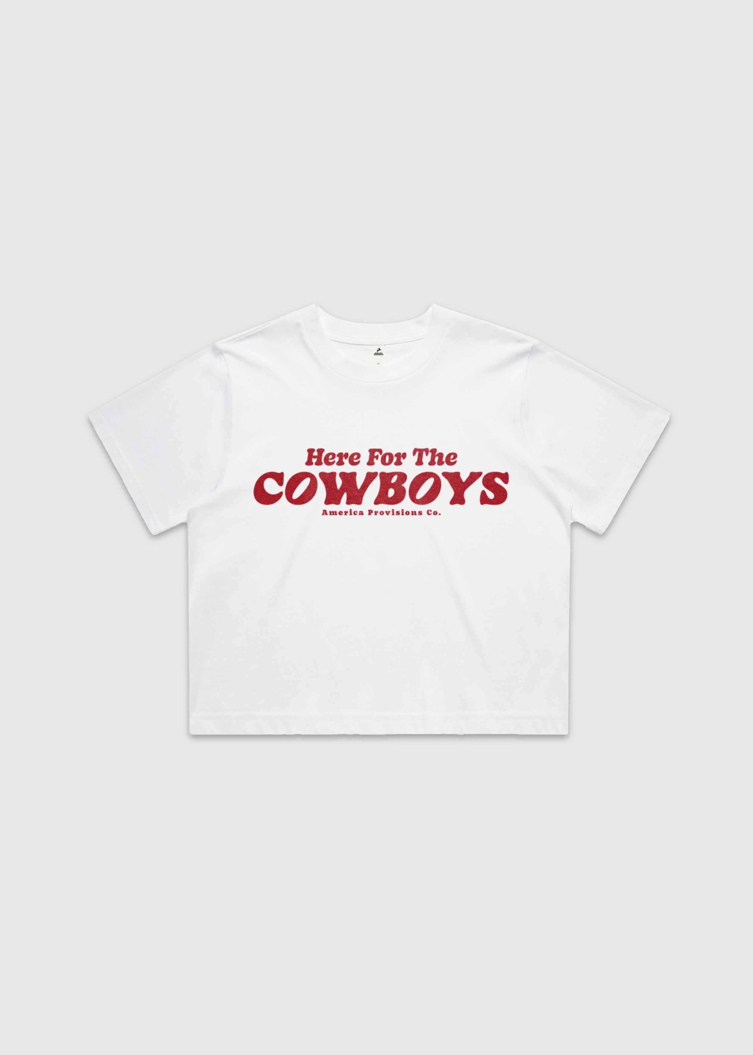 White cropped t-shirt with bold red “Here For The Cowboys” Western graphic, structured boxy fit, heavy cotton fabric, America Provisions apparel product photo on a neutral background.