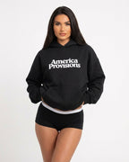 Woman wearing a black hoodie with 'America Provisions' text on a white background