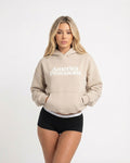 Woman wearing a Bone coloured hoodie with 'America Provisions' text on a white background