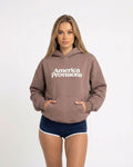 Woman wearing a Hazy Pink 'America Provisions' hoodie on a white background