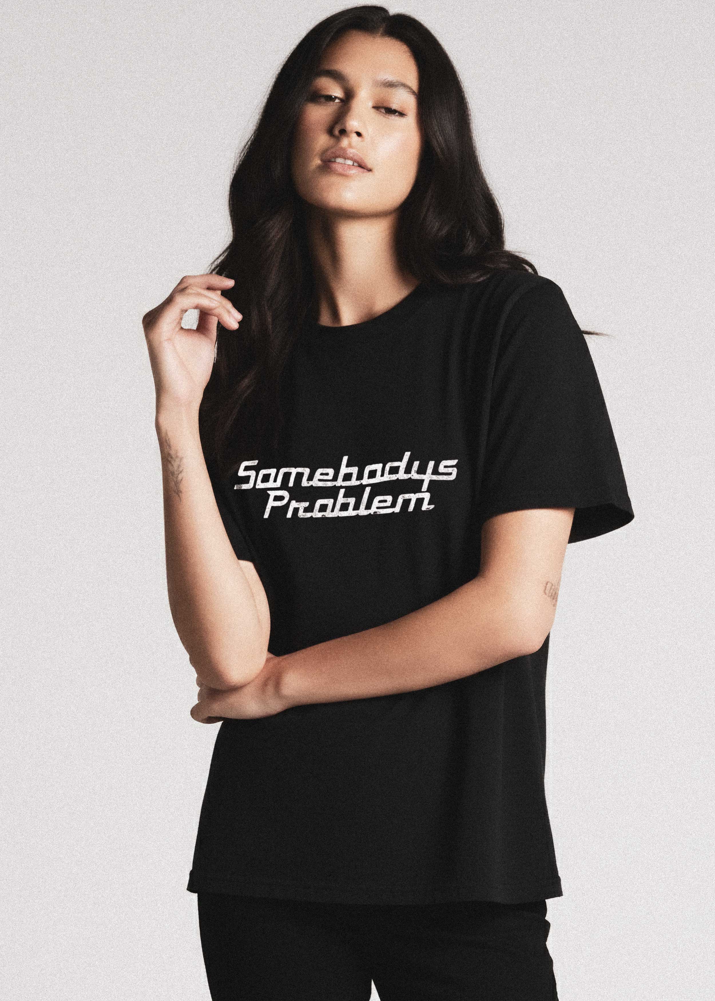 Female Model wearing a black t-shirt with 'Somebody's Problem' text on a plain background