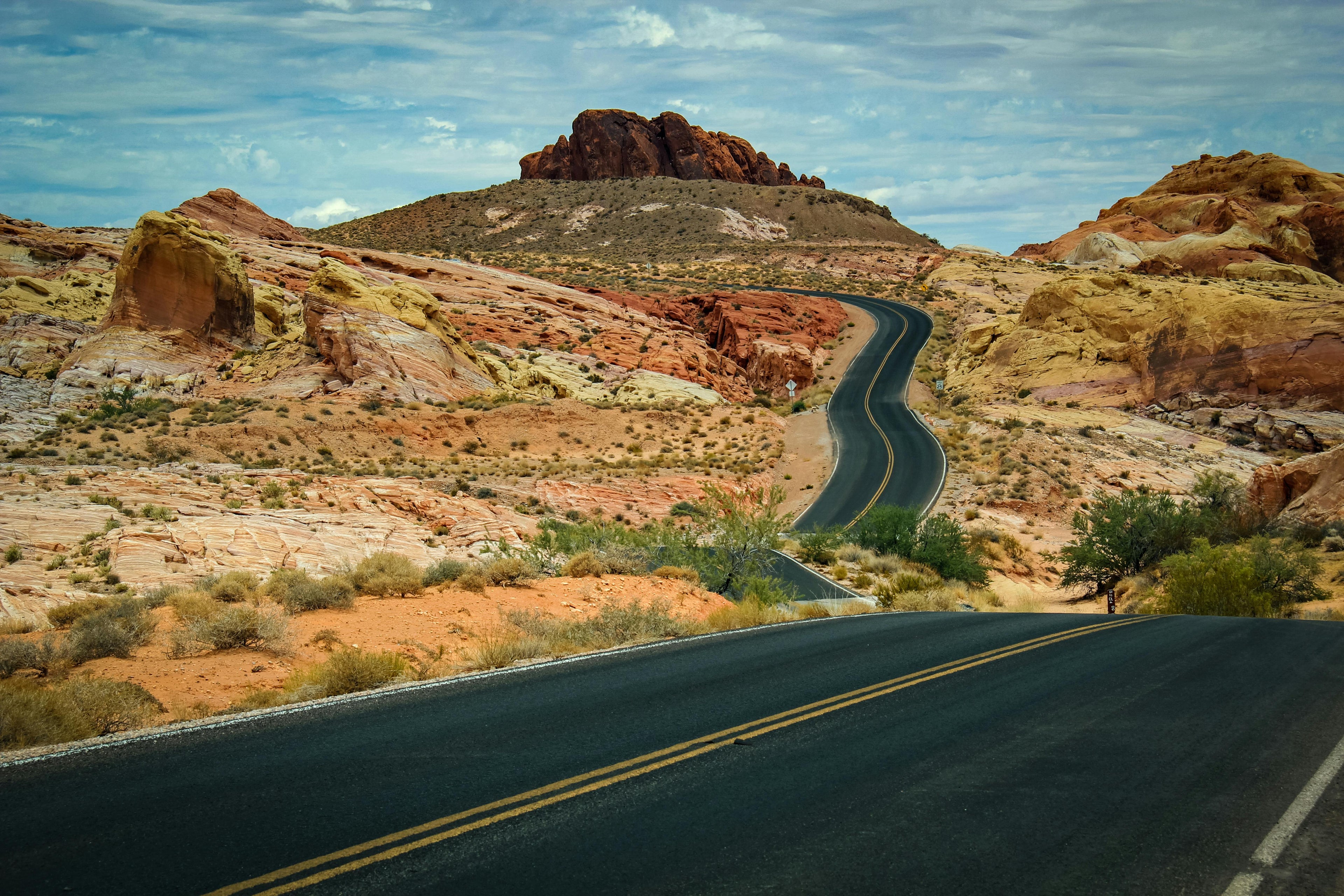 Winding road through a desert landscape with rocky hills and sparse vegetation.
