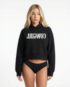 Reverse Cowgirl Woman wearing a cropped black hoodie with 'COWIRL' text on a white background